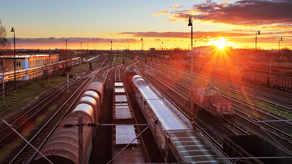 Rail yard with rows of freight cars at sunset